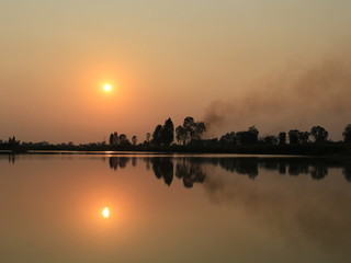  silhouette tree in asia with sunset.Tree silhouetted against a setting sun.Dark tree on open field dramatic sunrise and reflection in water.