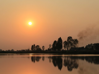 silhouette tree in asia with sunset.Tree silhouetted against a setting sun.Dark tree on open field dramatic sunrise and reflection in water.