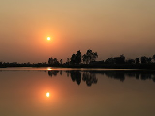  silhouette tree in asia with sunset.Tree silhouetted against a setting sun.Dark tree on open field dramatic sunrise and reflection in water.