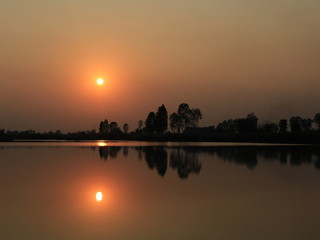  silhouette tree in asia with sunset.Tree silhouetted against a setting sun.Dark tree on open field dramatic sunrise and reflection in water.