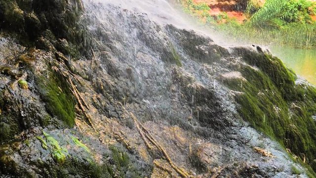 Agua cayendo de cascada y salpicando en roca en c&aacute;mara lenta