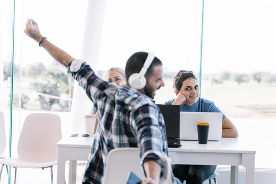 Boy stretching his arms and yawning sitting at a table in a coworking
