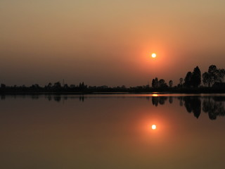  silhouette tree in asia with sunset.Tree silhouetted against a setting sun.Dark tree on open field dramatic sunrise and reflection in water.