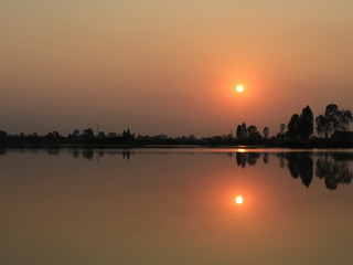  silhouette tree in asia with sunset.Tree silhouetted against a setting sun.Dark tree on open field dramatic sunrise and reflection in water.