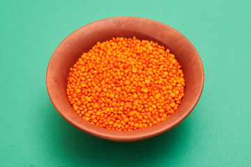 lentil grains in a plate on a green background.
