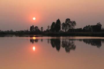  silhouette tree in asia with sunset.Tree silhouetted against a setting sun.Dark tree on open field dramatic sunrise and reflection in water.