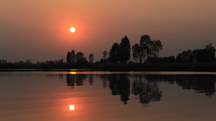  silhouette tree in asia with sunset.Tree silhouetted against a setting sun.Dark tree on open field dramatic sunrise and reflection in water.