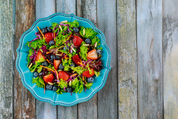Keto salad with strawberries, blueberries, spinach and red cabbage.