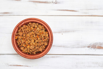 Grilled minced meat in a plate on a light wooden background.