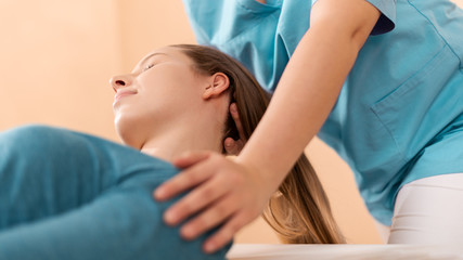 Female physiotherapist or a chiropractor adjusting patients neck. Physiotherapy, rehabilitation...