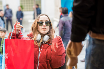 Beautiful young woman chooses clothes at display window