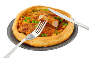Sausage and bean casserole served in a large Yorkshire pudding isolated on a white background