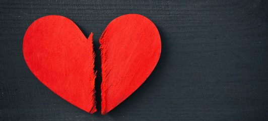 The broken red wooden heart on the wooden table. Concept of the divorce, broken relationship and end of the love