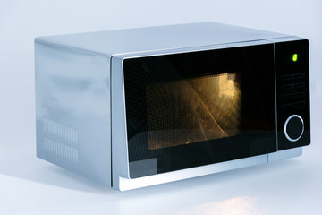 metal and electrical microwave oven with light on white background
