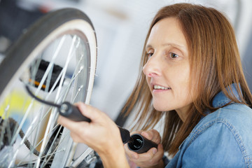 young woman pumps up the tires of her bike