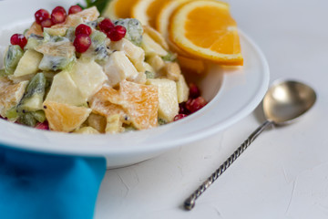 Diet fruit salad for breakfast. Kiwi orange banana and apple diced and seasoned with yogurt with honey. Healthy food, vegetarianism.