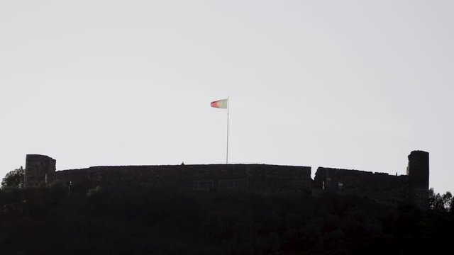 Portugese vlag is blowing in the wind on top of a castle in Aljezur