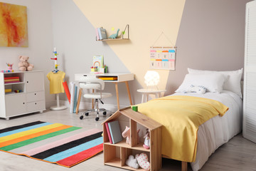 Stylish child room interior with comfortable bed and desk