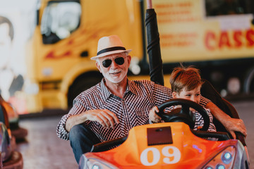 Grandfather and grandson having fun and spending good quality time together in amusement park. They...