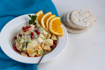 Diet fruit salad for breakfast. Kiwi orange banana and apple diced and seasoned with yogurt with honey. Healthy food, vegetarianism.