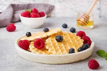 Corrugated waffle cookies with fresh raspberries and blueberries on a concrete background. Copy space.