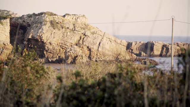 Rock formation through some bushes in the Algarve protugal during sunset CLOSE
