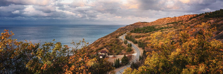 Landscape hills, sea, sky, clouds and road running along the coast.