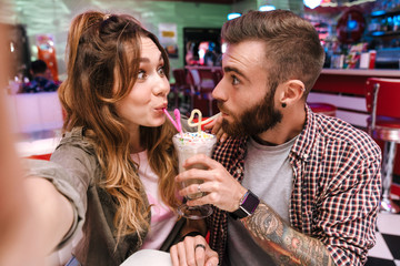 Couple in retro bright street food cafe take a selfie by camera.