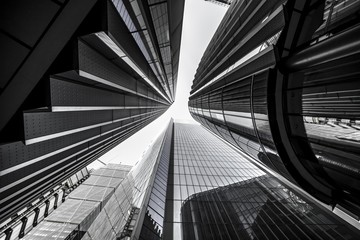 Low angle greyscale of modern skyscrapers with glass windows under sunlight - obrazy, fototapety, plakaty