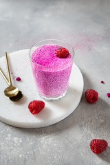 Chia pudding with fresh raspberries, honey and pink matcha or spirulina in a glass. Superfoods, detox, dieting concept. Side view, copy space