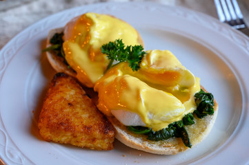 Weekend vegetarian brunch in Scotland with two eggs benedict on homemade muffuns with spinach and yellow hollandaise sauce.