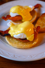 Weekend brunch in Scotland with two eggs benedict on homemade muffuns with roasted bacon and yellow hollandaise sauce.