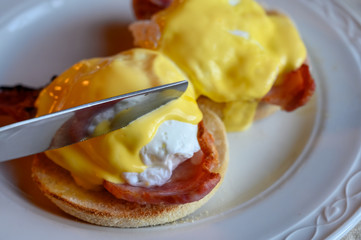 Weekend brunch in Scotland with two eggs benedict on homemade muffuns with roasted bacon and yellow hollandaise sauce.