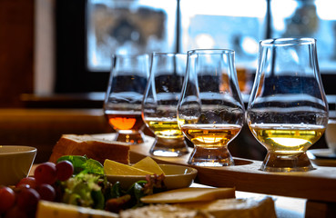 Tasting of original scottish cheese and whisky, plate with scottish cheeses and variety of Scotch in glasses