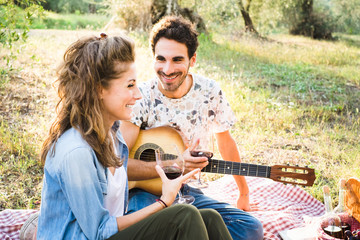 Beautiful couple in love having a picnic drinking wine