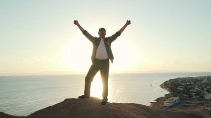 Fototapeta premium Senior traveler raise his hands in success gesture at sunrise