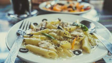 Yummy pasta on cafe table. Closeup plate with portion of tasty pasta with cream sauce placed on table in restaurant