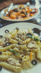 Yummy pasta on cafe table. Closeup plate with portion of tasty pasta with cream sauce placed on table in restaurant
