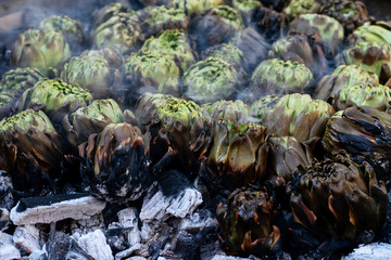 Fresh exotic artichokes baking in brazier on the coal. Holiday, market place.