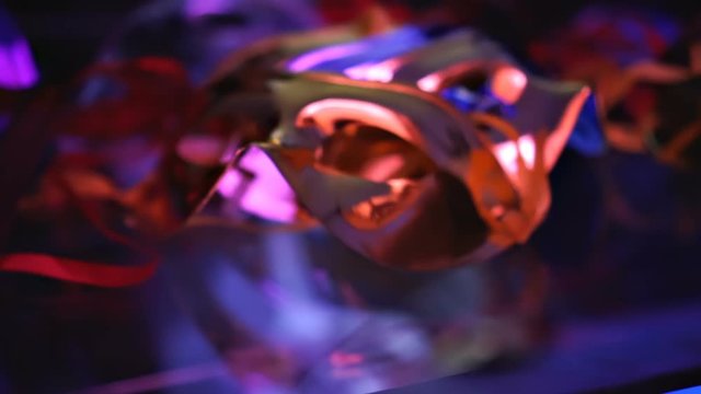 Golden and Shiny traditional masquerade masks on a reflective surface, colorful semi-dark lighting, camera fly-through Close up
