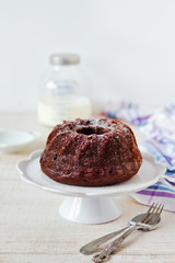 Chocolate bundt cake with icing sugar on wooden table, rustic style