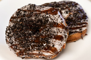 Two stacked donuts with vanilla icing, chocolate drizzle, and cookie crumbles.