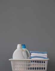 Plastic bottles for packaging laundry detergent for washing clothes with colored caps in a plastic basket. Space for text. Bio organic product.