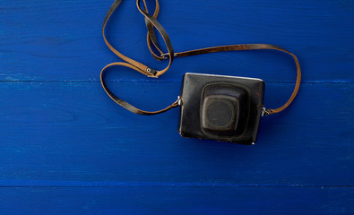 Vintage film camera in a leather case on a wooden blue background