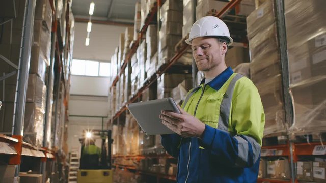 Male manager man standing in big modern warehouse with tablet compute