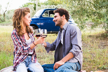 Beautiful couple in love having a picnic drinking wine