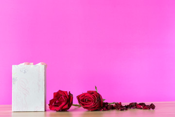 Gift box and red rose in the table on color pink background,