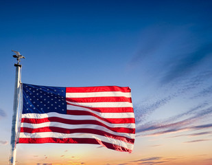 An American Flag waving in the wind against a blue sky
