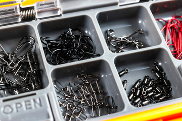 Opened tackle box with fishing hooks and accessories. Fishing hooks in box sections. Case for tackle elements. Fishing accessories background close-up.
