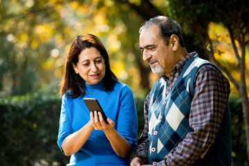 Senior woman sharing media content with her husband using mobile phone